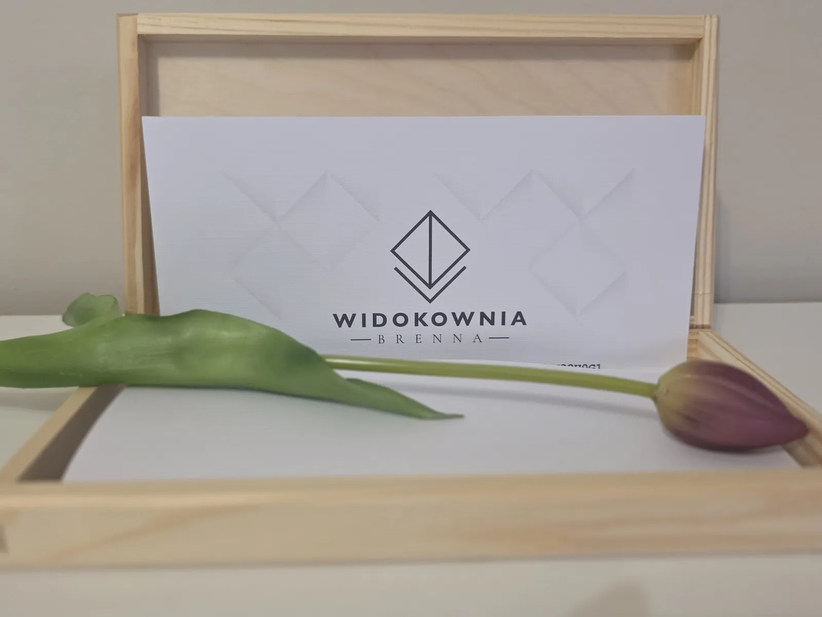 Otevřená dřevěná krabička s poukazem Widokownia a tulipánem